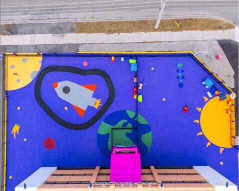 Colorful children's classroom wall mural with a rocket ship, heart, sun and planet at Little Galaxy