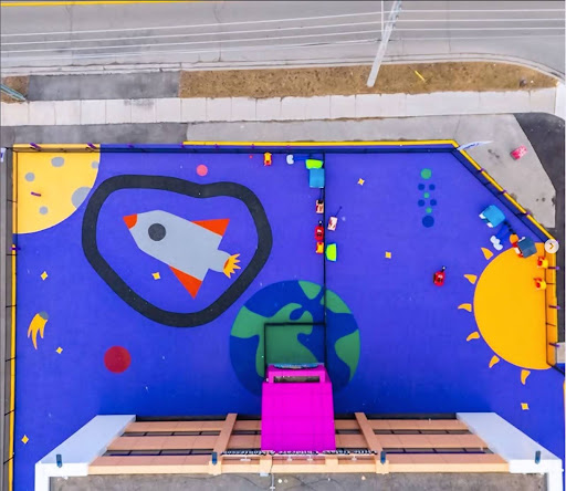 Colorful children's classroom wall mural with a rocket ship, heart, sun and planet at Little Galaxy